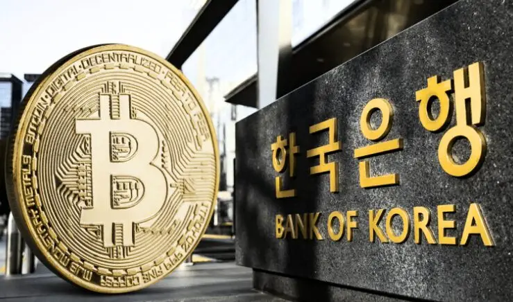 Bitcoin coin next to Bank of Korea sign in gold lettering