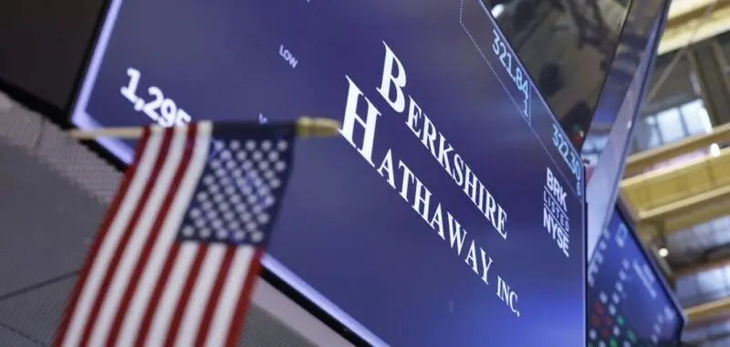 Berkshire Hathaway sign on trading floor with American flag in background