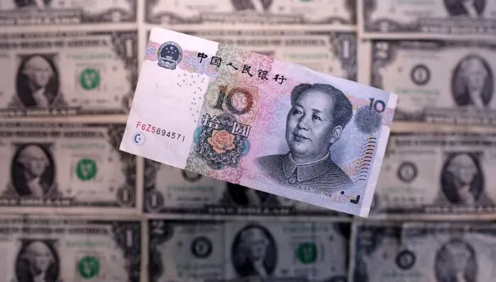 Chinese yuan banknote against background of US dollar bills