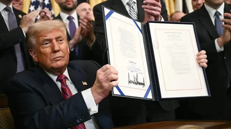 President Trump signing the GENIUS Act into law, displaying the signed legislation