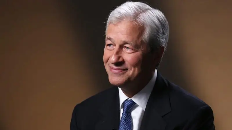 Jamie Dimon smiling in formal suit with brown background