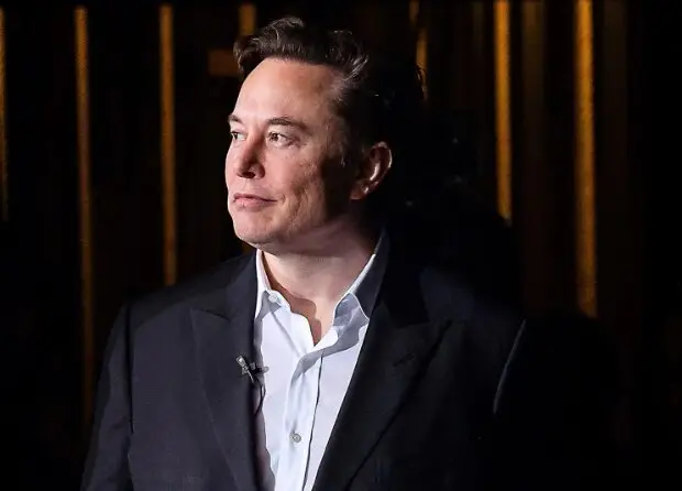 Elon Musk in formal attire against dark background
